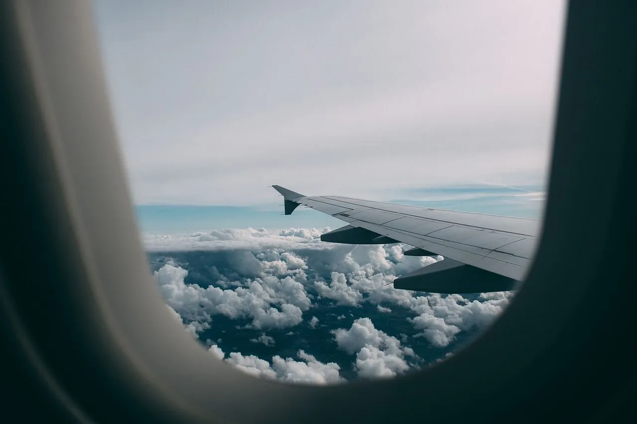 Blick aus dem Kabinenfenster auf die Tragfläche und ein Wolkenfeld darunter