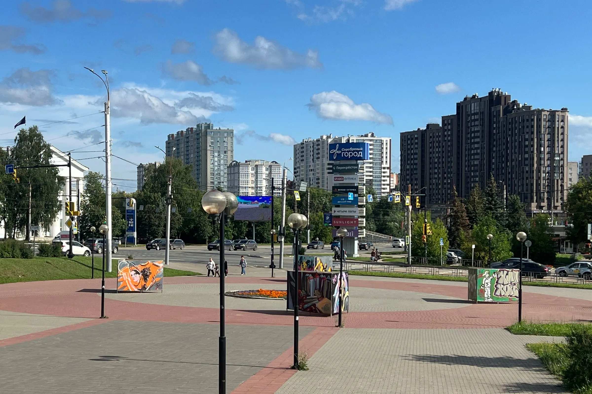 Ein weiter gepflasterter Platz in Iwanowo mit Laternenreihen, dahinter die Durchgangsstraße und die Hochhäuser der Stadt