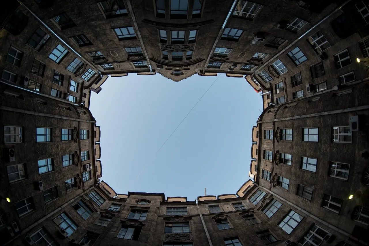 Blick aus einem Petersburger Innenhof senkrecht nach oben, die Fensterreihen der Wohnhäuser umschließen ein Stück Himmel