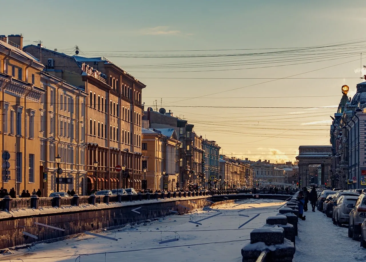 Die Uferstraße eines zugefrorenen Petersburger Kanals im Winterlicht, links eine Reihe klassizistischer Hausfassaden