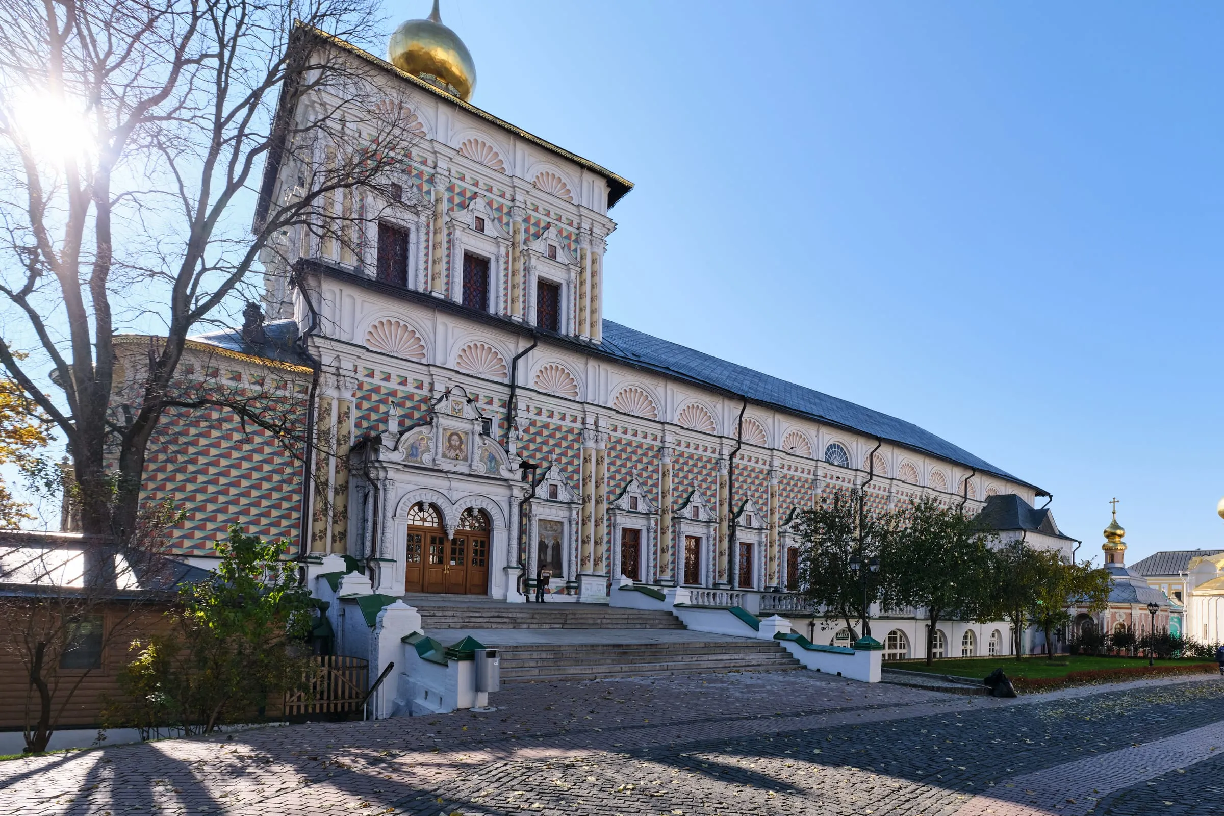 Die schachbrettartig bemalte Fassade der Refektoriumskirche in der Troize-Sergijew-Lawra mit ihren Muschelbögen und der goldenen Kuppel